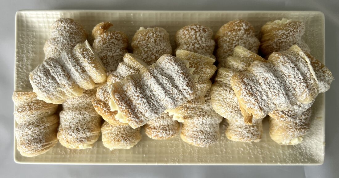 Box of ten mini PastryVille cream rolls, dusted with powdered sugar
